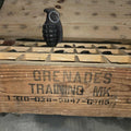 Wooden crate labeled 'Grenades Training MK.' with a grenade on top, on a wooden surface.