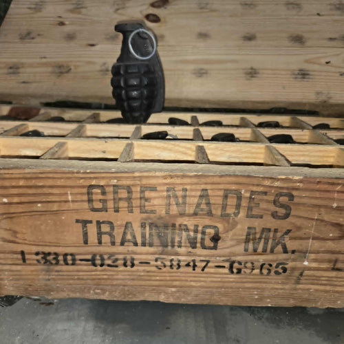 Wooden crate labeled 'Grenades Training MK.' with a grenade on top, on a wooden surface.