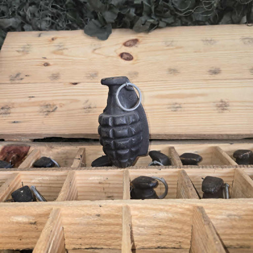 Black grenade model on a wooden grid with green foliage in the background
